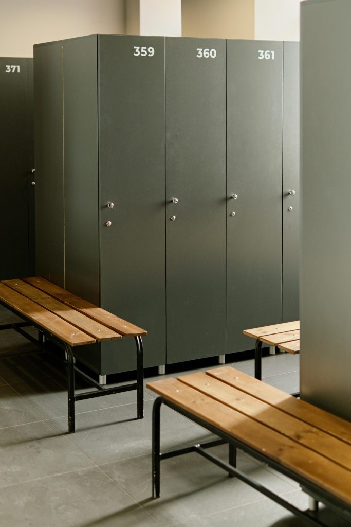 Spacious locker room featuring grey lockers and wooden benches, ideal for fitness centers.